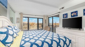 Un dormitorio con una cama grande, televisión y balcón con vistas.