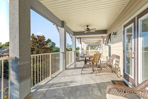 Relax in a serene outdoor space with a patio, seating area, and ceiling fan, offering a view of the surrounding landscape.
