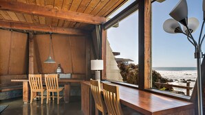 Un intérieur en bois comprenant un coin repas, une lampe et une vue sur l’océan.