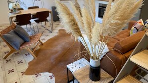 A modern living room with a brown leather sofa, a coffee table with a vase of pampas grass, and a dining area with a white table and chairs. - Townhouse Terrace Beauduc, Arles (Arles)