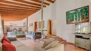 A spacious living room with a high ceiling, a fireplace, a dining area, and a kitchen. - El Ranchon by Rentallorca (Port de Pollença)