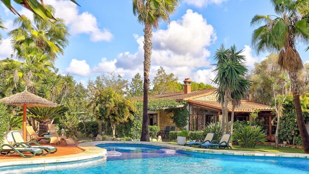 A pool area with lounge chairs and a thatched-roof structure. - El Ranchon by Rentallorca (Port de Pollença)