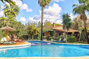 Zona de piscina con sillones de descanso y una estructura de techo de paja.