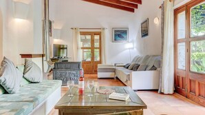 A cozy living room with a sofa, a coffee table with wine glasses, and a fireplace. - El Ranchon by Rentallorca (Port de Pollença)