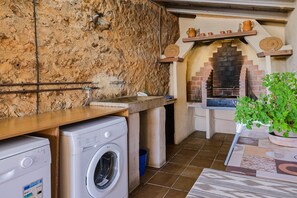 Compact kitchen with brick oven, washing machine, and sink.