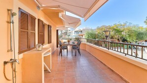 A balcony with a table and chairs, a hanging light fixture, and a view of the surrounding buildings and trees.