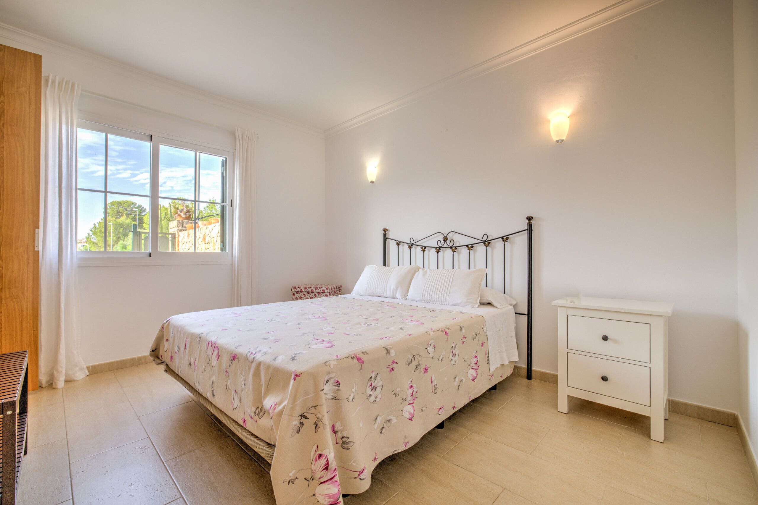 A bedroom with a bed, bedside table, and a window with curtains.