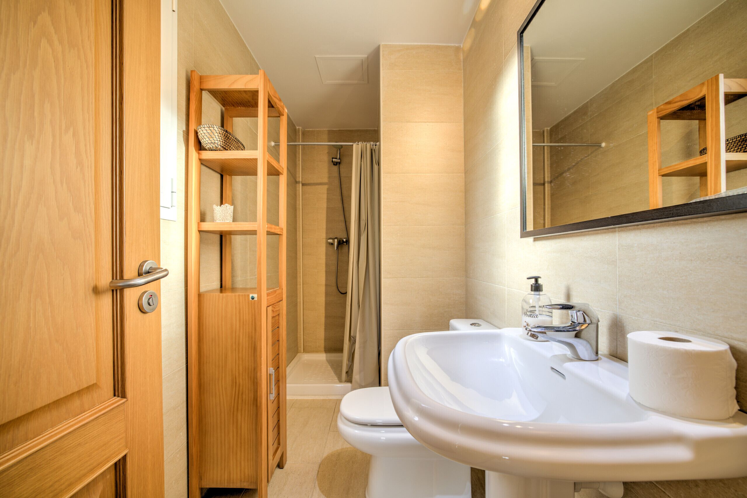 A bathroom with a wooden cabinet, a toilet, a sink, and a shower.