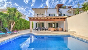 Uma casa moderna com piscina, área de estar externa e escadaria que leva a uma varanda.