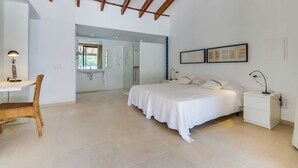 Camera da letto con un letto grande, una scrivania e una sedia. Si intravede un bagno sullo sfondo.