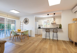 Una cocina moderna con armarios blancos, una mesa de comedor con sillas y una barra con taburetes.