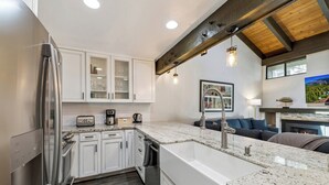 Eine moderne Küche mit weißen Schränken, einem Edelstahlkühlschrank, Granit-Arbeitsplatten und einem eingebauten Backofen.