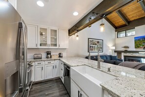 A modern kitchen with white cabinets, a stainless steel refrigerator, granite countertops, and a built-in oven.