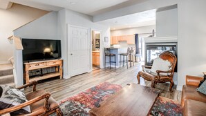 A spacious living room with a wooden entertainment center, a large flat-screen TV, a dining area with a bar, and a kitchen in the background. - Kingdom Park Townhome: Nice Space, On Shuttle Route (Breckenridge)