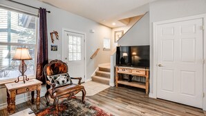 A living room with a wooden floor, a leather chair, a TV stand, and a staircase. - Kingdom Park Townhome: Nice Space, On Shuttle Route (Breckenridge)