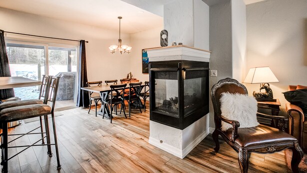 A living room with a fireplace, wooden flooring, and a dining area with chairs and a table. - Kingdom Park Townhome: Nice Space, On Shuttle Route (Breckenridge)