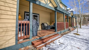 A covered porch with outdoor seating, a grill, and a snow-covered ground. - Kingdom Park Townhome: Nice Space, On Shuttle Route (Breckenridge)