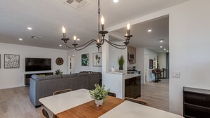 Una cocina moderna con comedor, televisor integrado y una araña.