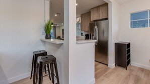 Una cocina moderna con refrigerador de acero inoxidable, armarios de madera y una pequeña zona de bar con taburetes.
