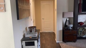 Un couloir avec un banc en bois, une porte et un meuble contenant des objets décoratifs.