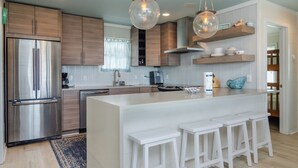 Een moderne keuken met houten kastjes, roestvrijstalen apparatuur en een centraal eiland met barstoelen.