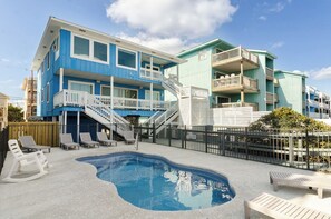 A two-story building with a swimming pool, outdoor seating, and a staircase leading to the upper floor.