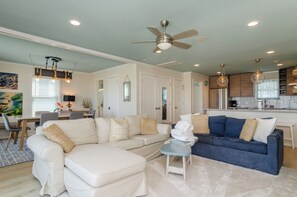 A modern living room with a sectional sofa, a blue sofa, and a dining area with a table and chairs.