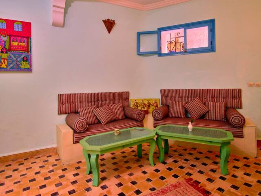 A room with two striped sofas, a green coffee table, a patterned rug, and a wall with a framed picture and a window.