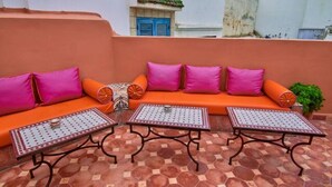 Un espacio al aire libre con cojines naranja y mesas con diseños.