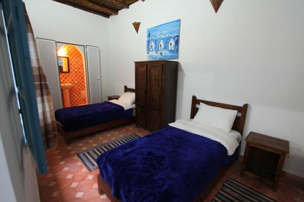 Una habitación con dos camas, un armario, un cuadro y una mesita.
