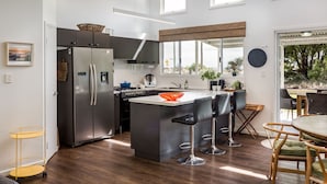 Una cocina moderna con una isla central, electrodomésticos de acero inoxidable y una zona de comedor con taburetes de bar.