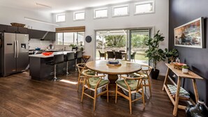 Una cocina moderna con una isla central, taburetes de bar y una mesa de comedor con sillas.