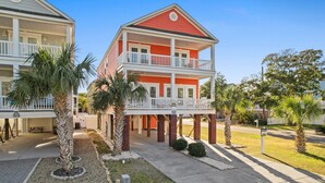 A two-story hotel with a red and white exterior, a balcony on the second floor, and palm trees in the front yard. - Walk to Beach 6BR Home w/ Private Pool & Beachside Porches (Surfside Beach)