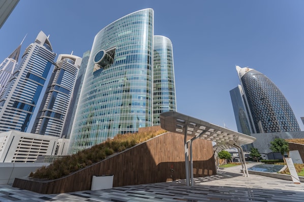 Un quartier urbain moderne, caractérisé par des immeubles de grande hauteur, une promenade piétonne et une structure composée de panneaux solaires.