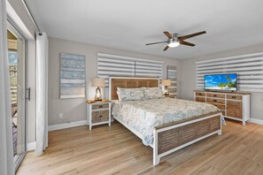 Una camera da letto con un letto, comodini, una TV e una ventola a soffitto.