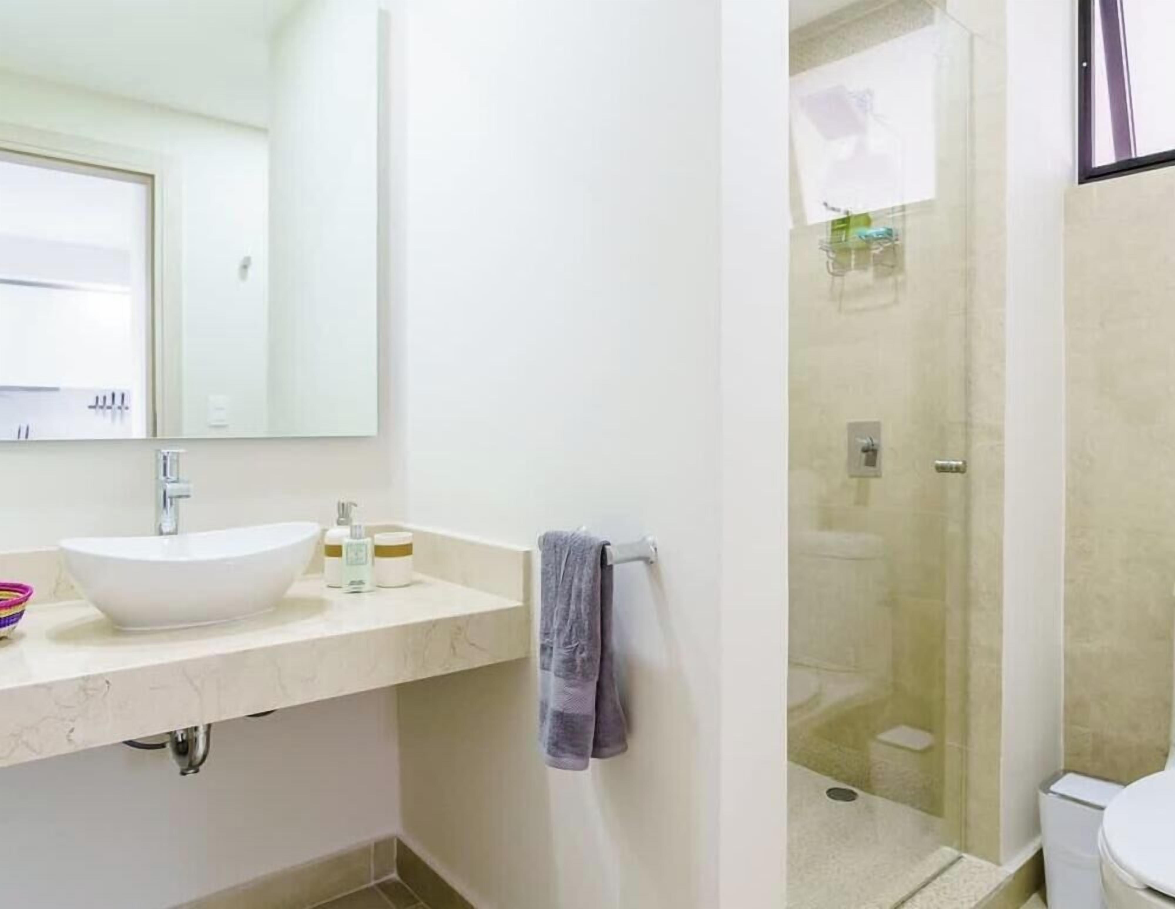 A bathroom with a white sink, a mirror, a towel rack, and a glass-enclosed shower area.