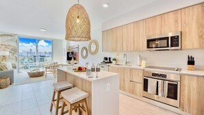 Een moderne keuken met een centraal eiland, houten kastjes en uitzicht op de stad.
