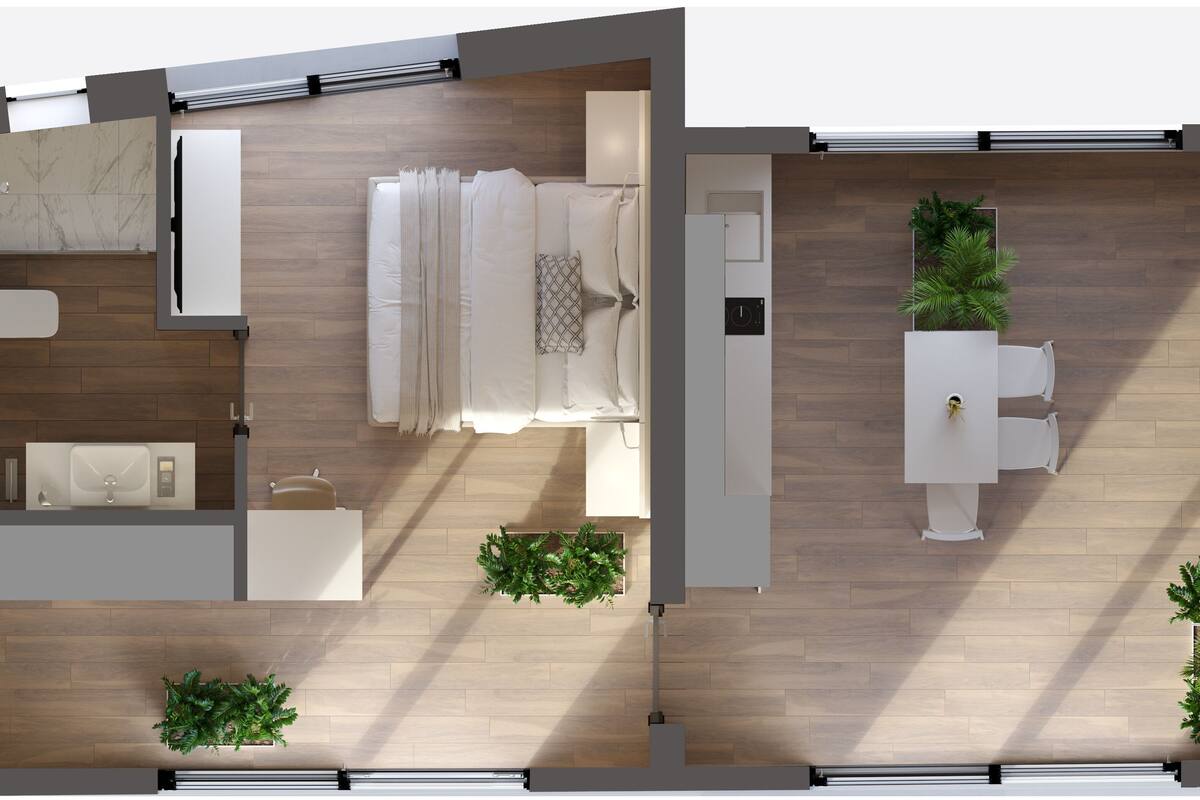 Een moderne hotelkamer met een houten vloer, een bed met witte lakens, een kleine badkamer met een wastafel en toilet, en een zithoek met een tafel en stoelen.