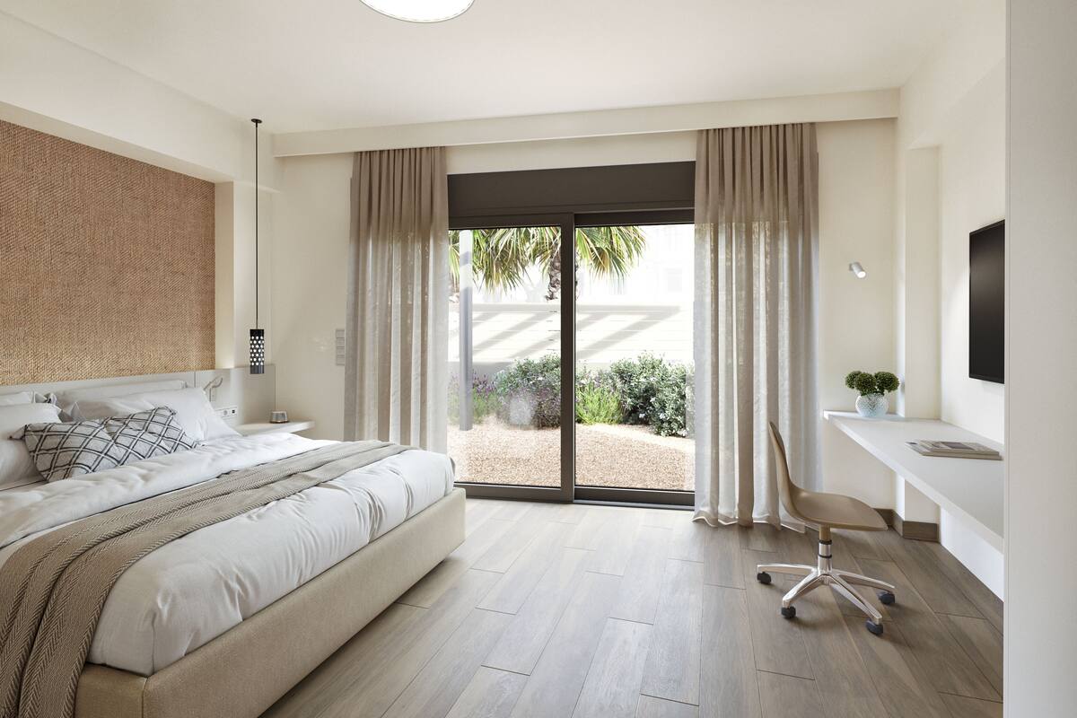 Een moderne slaapkamer met een groot bed, een bureau en uitzicht door de glazen deuren.