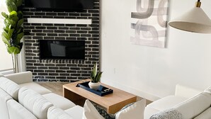 A modern living room with a white sofa, a wooden coffee table, and a black and white brick fireplace. - Luxury Downtown Spacious 3 bedroom New Modern Townhome (Provo)