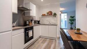 Eine moderne Küche mit weißen Schränken, einem Holztisch und Blick ins Freie.