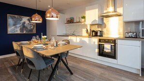 A modern kitchen with white cabinets, a built-in oven, and pendant lighting. - Bright Contemporary 2BED Apartment by Old Trafford (Manchester)