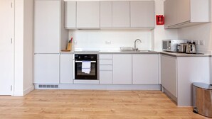 Een moderne keuken met witte kasten, een ingebouwde oven, een magnetron en een spoelbak.