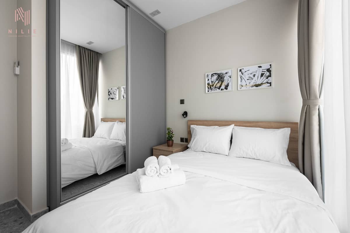 A hotel room with a large bed, a bedside table with a plant, and artwork on the wall.