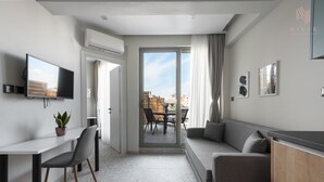 Ein modernes Wohnzimmer mit einer Couch, einem Fernseher und einem Essbereich mit Stühlen und einem Tisch.