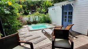 Un espace piscine comprenant une petite piscine, entourée d’une terrasse en bois, et aménagé avec des chaises et une table.