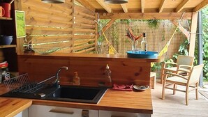 Une cuisine en bois avec un évier noir, un plan de travail en bois et un luminaire suspendu.