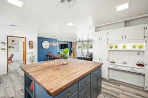 Une cuisine moderne avec un îlot central en bois, des armoires blanches et un mur d’accent bleu.