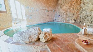 A stone-walled indoor pool with a stone bench and a bottle of wine. - Amazing Villa Boron! View of the Sea, Pool, and Hot Tub (Nice)
