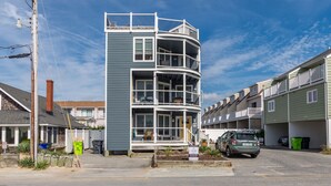 Un immeuble à plusieurs étages, doté de balcons et de grandes fenêtres, situé dans un quartier résidentiel où l’on peut voir des voitures garées à proximité.